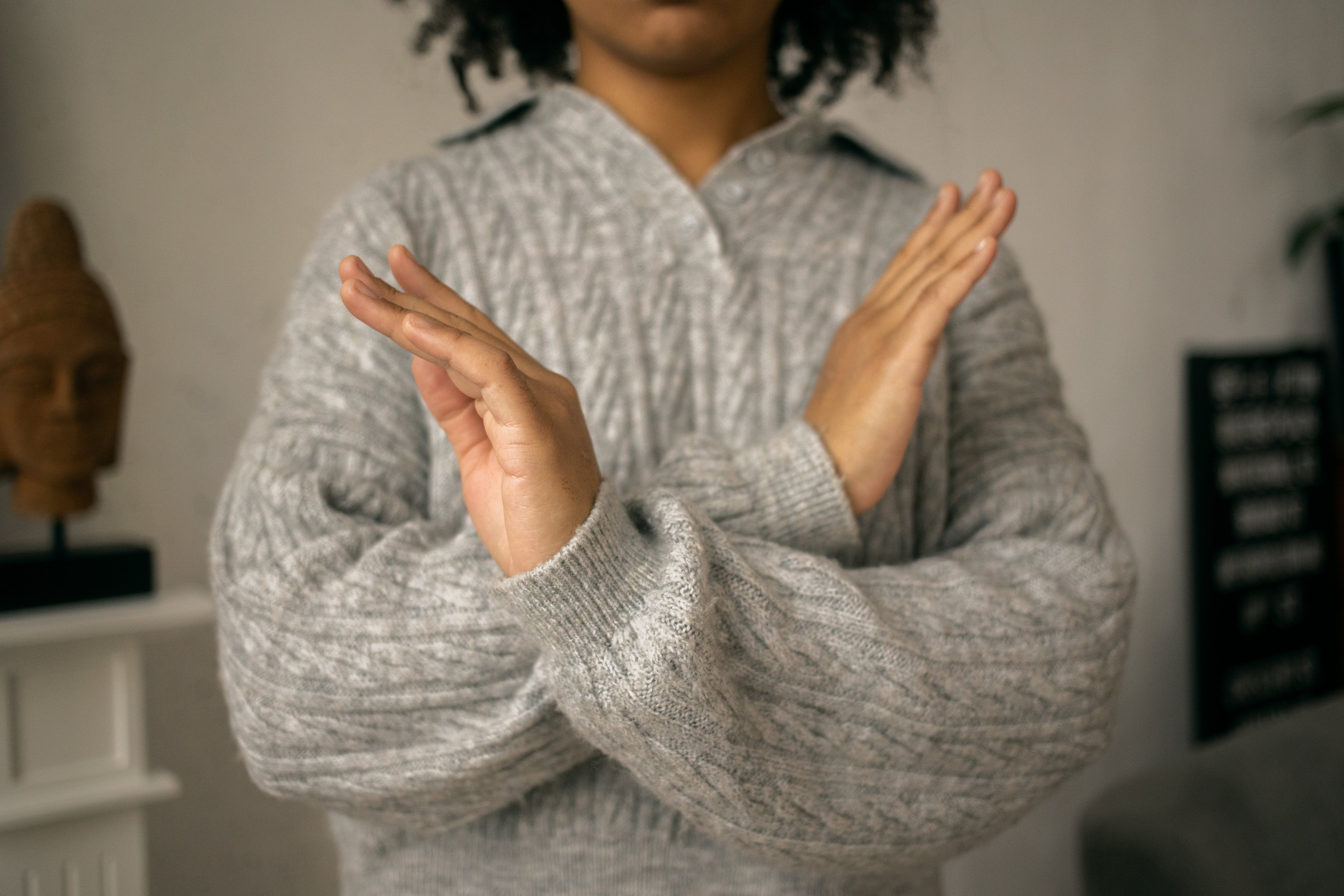 This is a photo of a person holding their hands in front of their body crossed over to make an X. The X symbolizes 'no'.